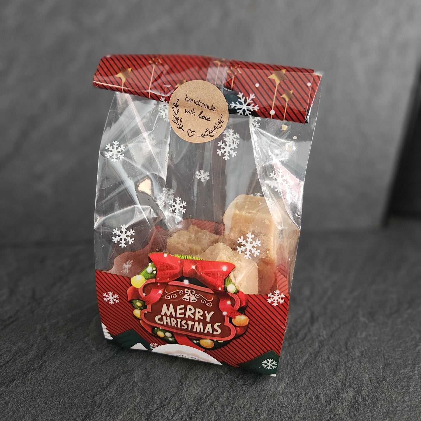 Christmas-themed fudge gift bag with a clear window showing treats inside on a dark background