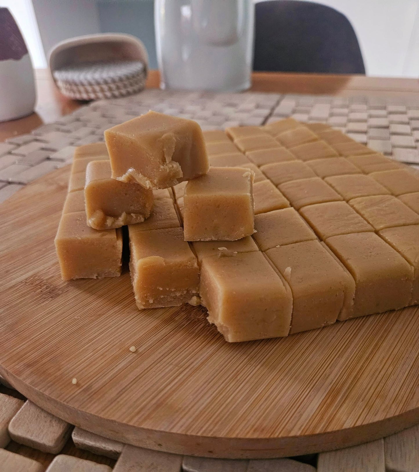 Cubes of fudge on a wooden cutting board with a blurred background