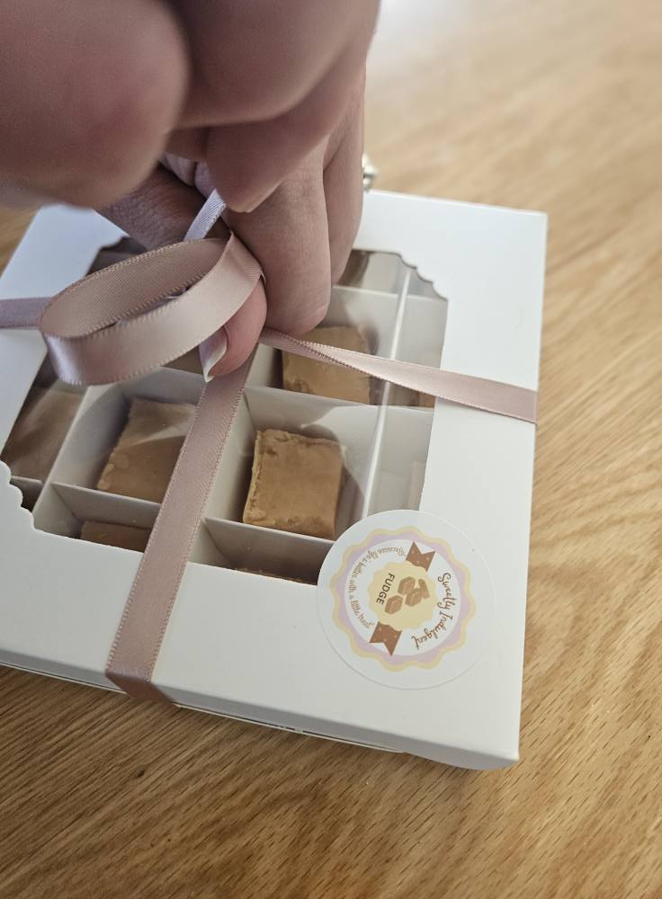 Fudge gift box being tied with pink ribbon by hand