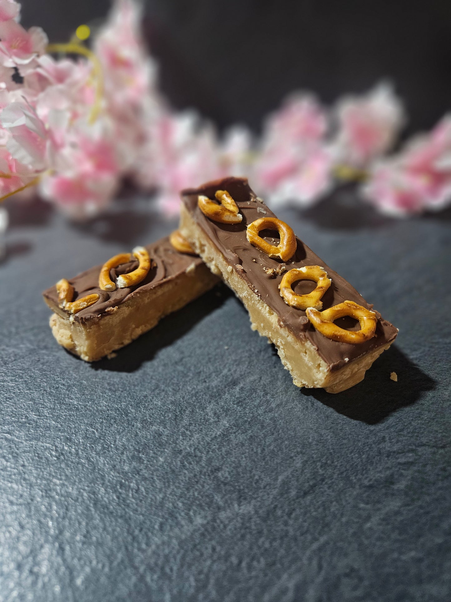 pretzel and milk chocolate fudge bar with floral and grey background