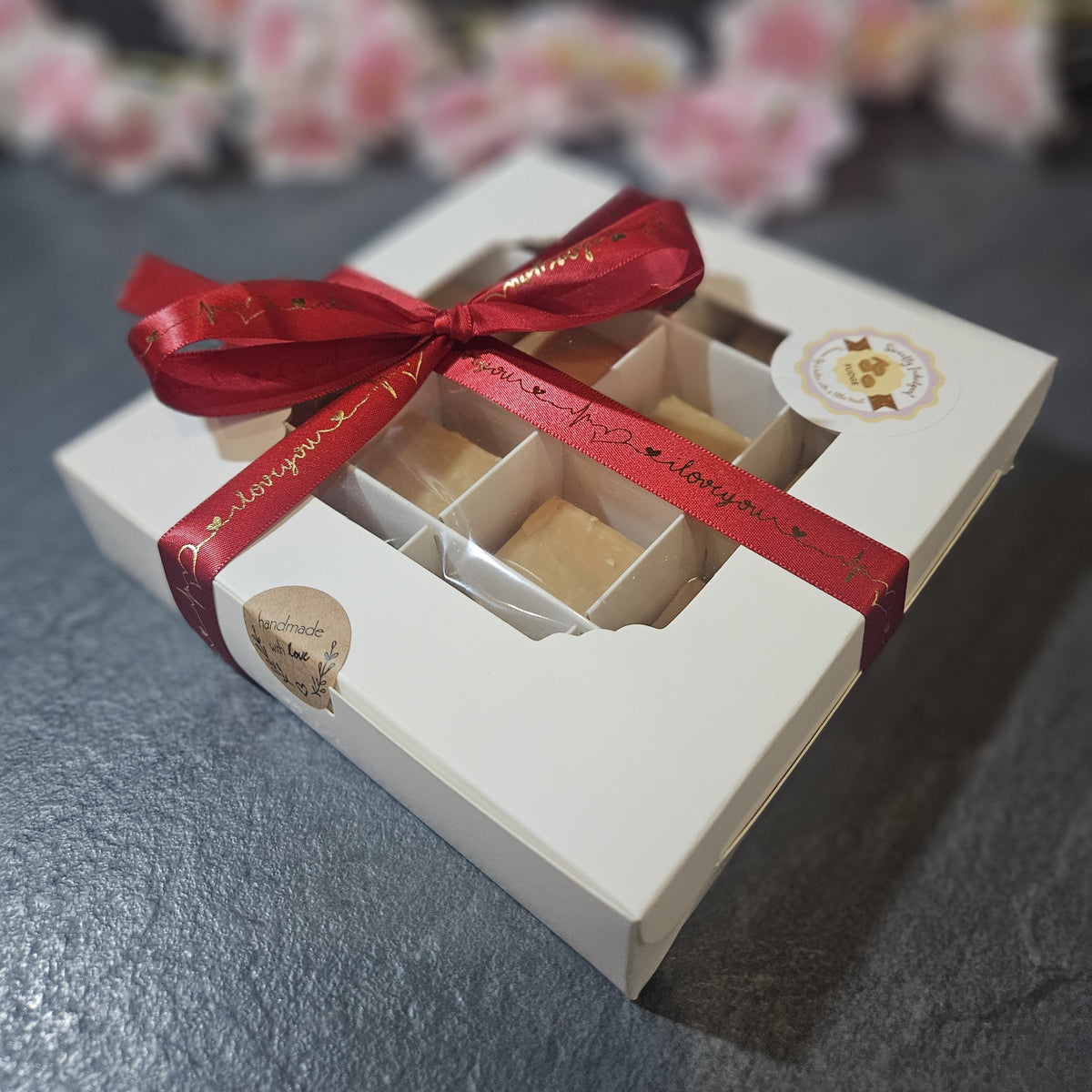 Gift box with a red ribbon  that says I love You. On a grey surface