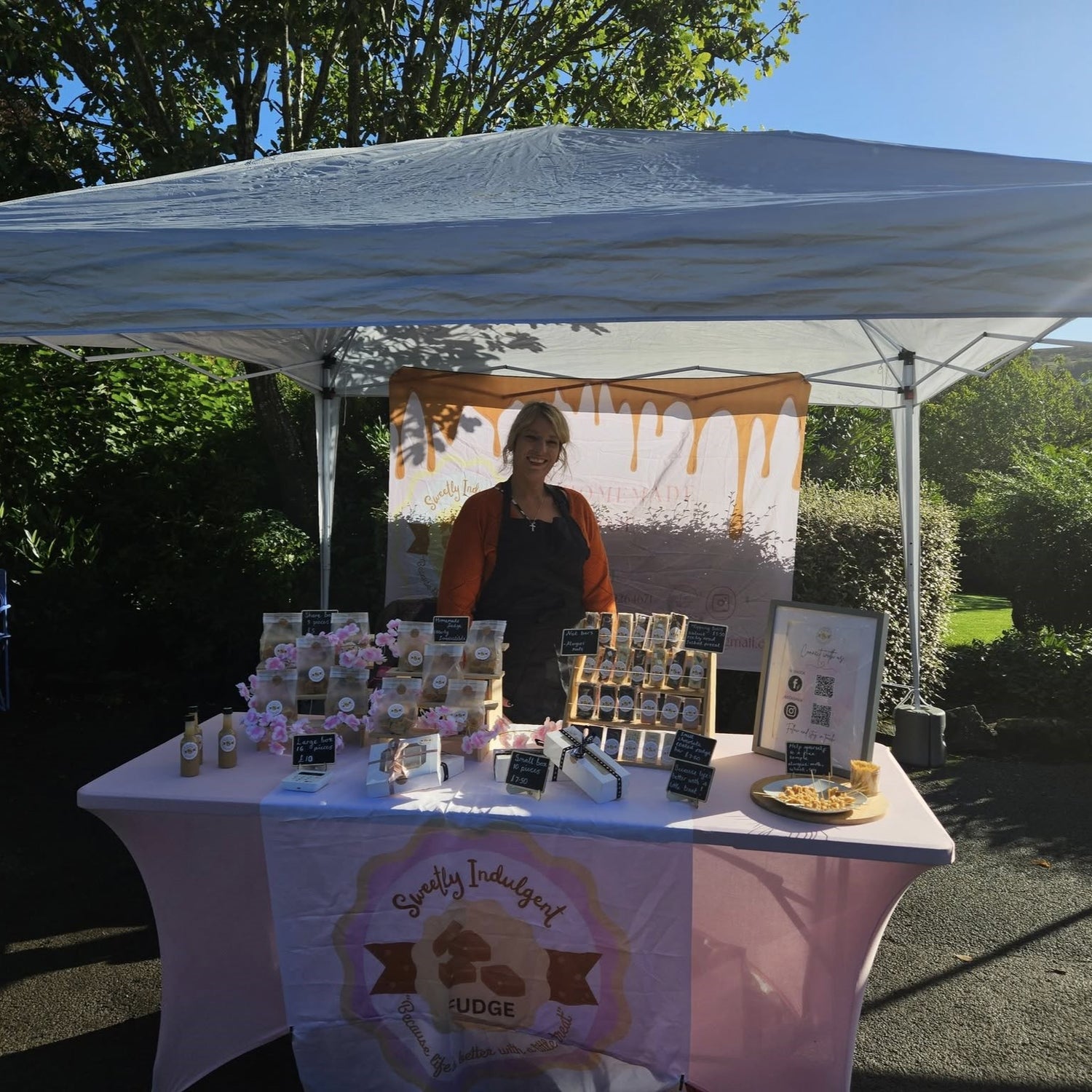 Becky owner of Sweetly Indulgent Fudge stood at market stall in Yorkshire displaying products and company branding  