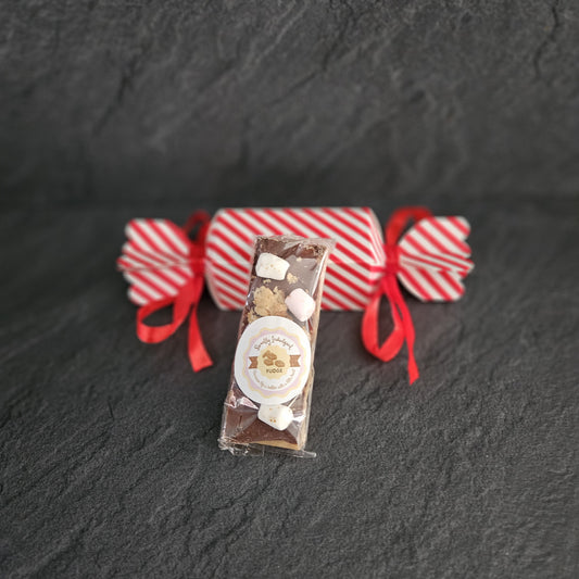Decorative fudge box with red ribbons on a dark textured surface