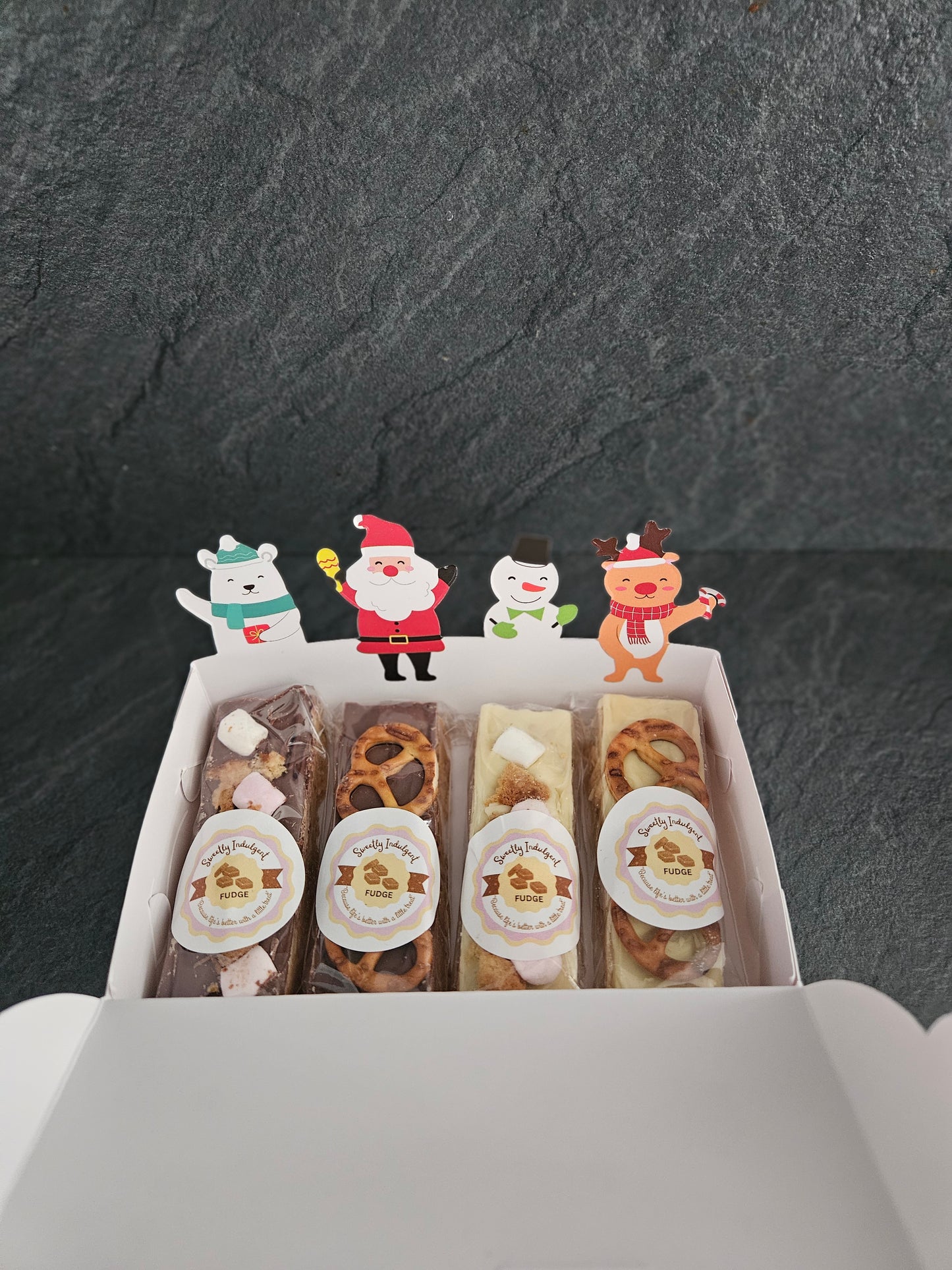 Assorted fudge bars in a box with decorative stickers on a dark surface