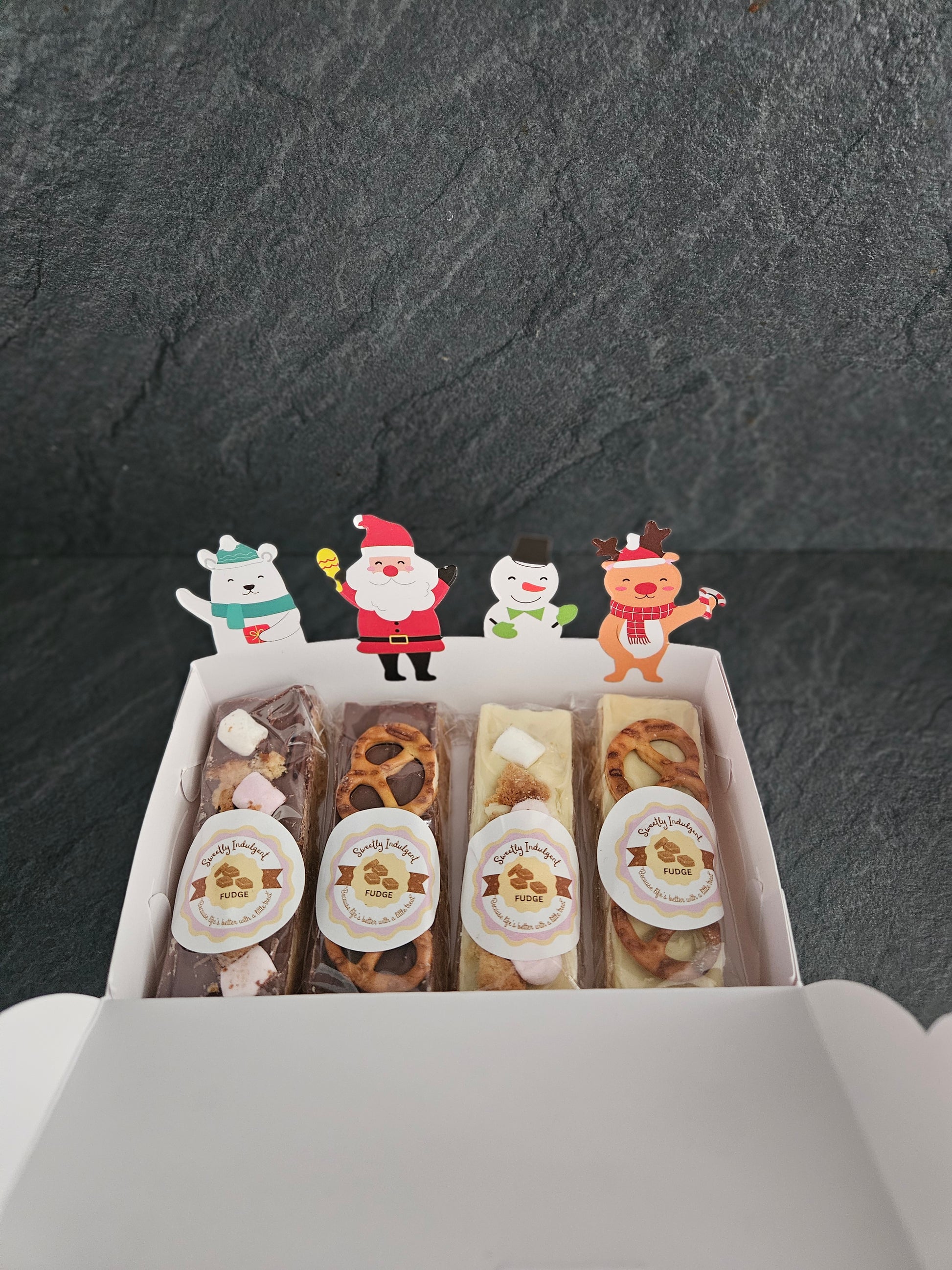 Assorted fudge bars in a box with decorative stickers on a dark surface