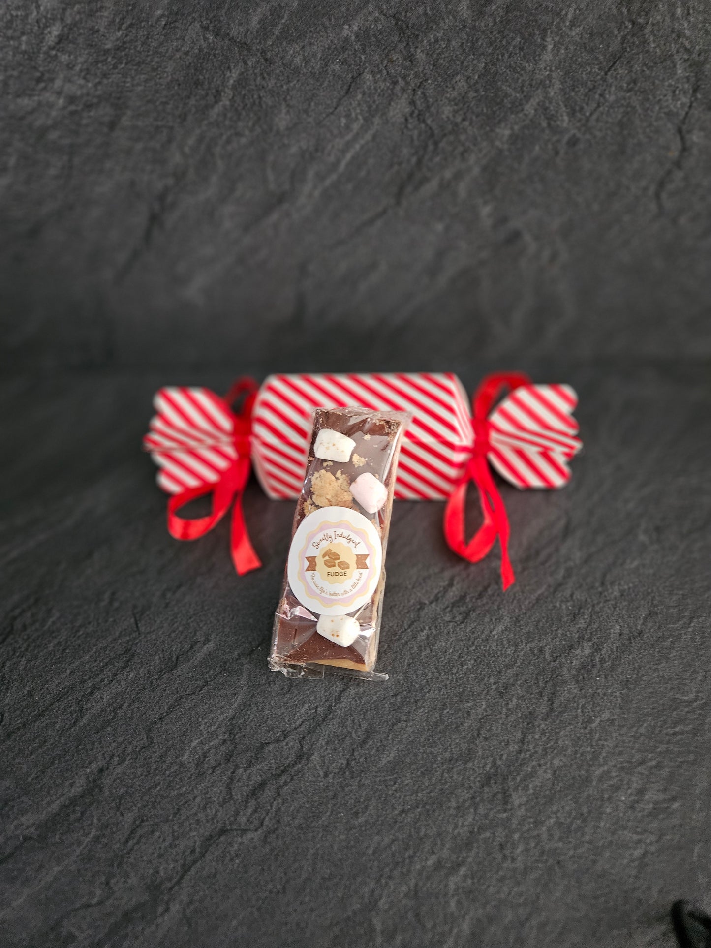 Decorative fudge box with red ribbons on a dark textured surface