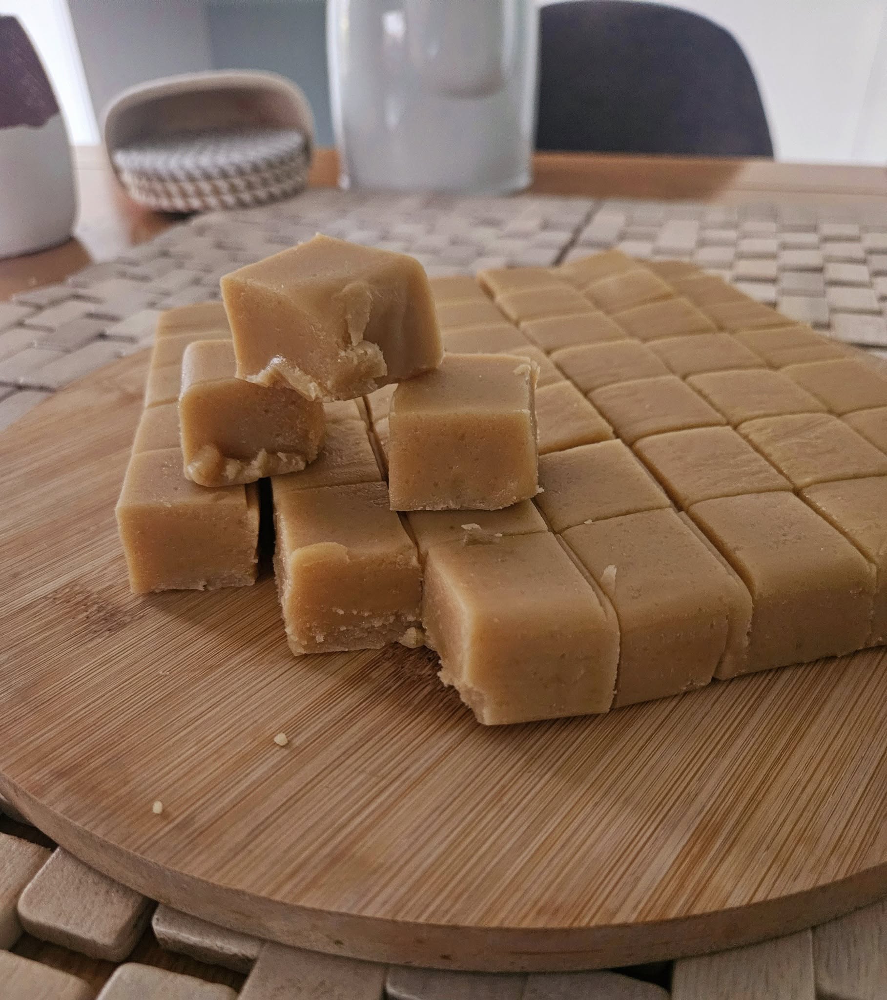 Cubes of fudge on a wooden cutting board with a blurred background