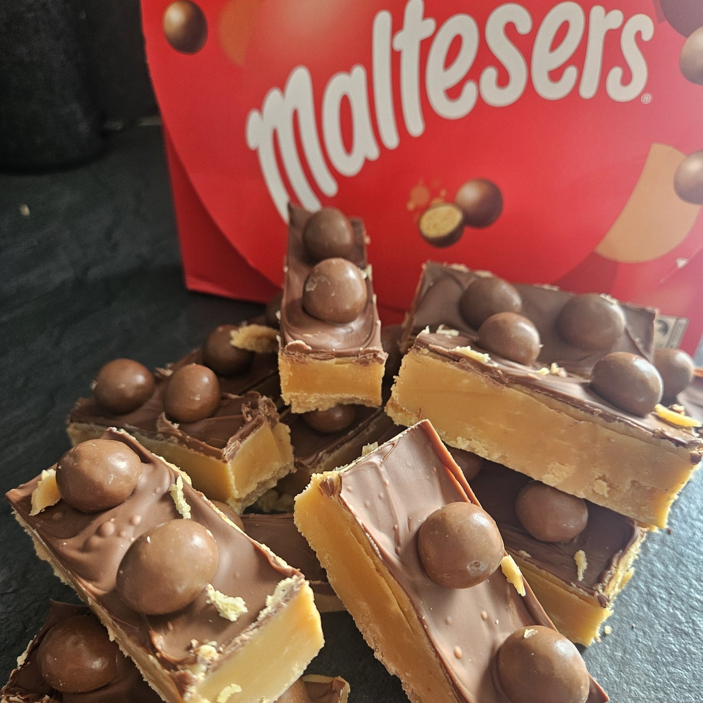 Large fudge bars topped with milk chocolate and maltessers on dark surface