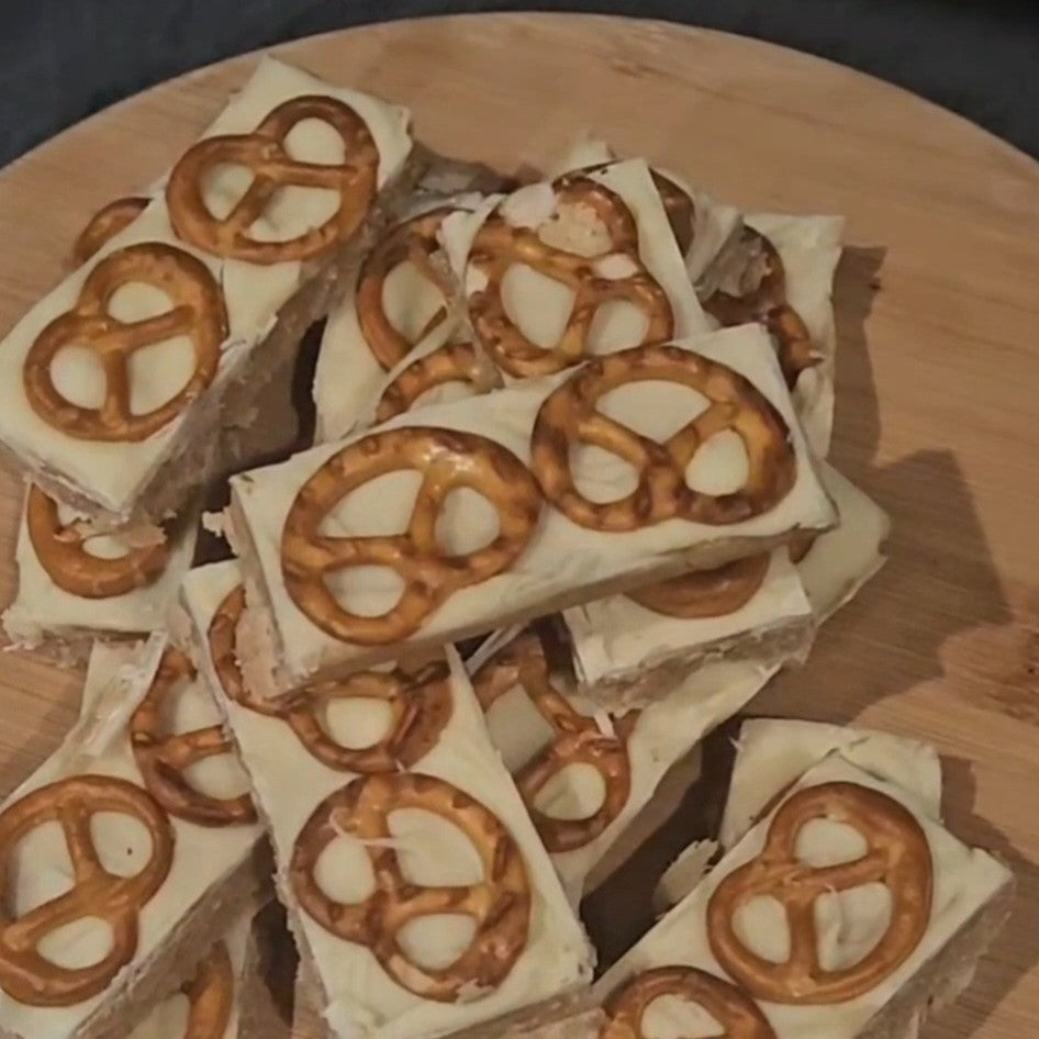 buttery fudge bars topped with pretzel pieces on a wooden surface