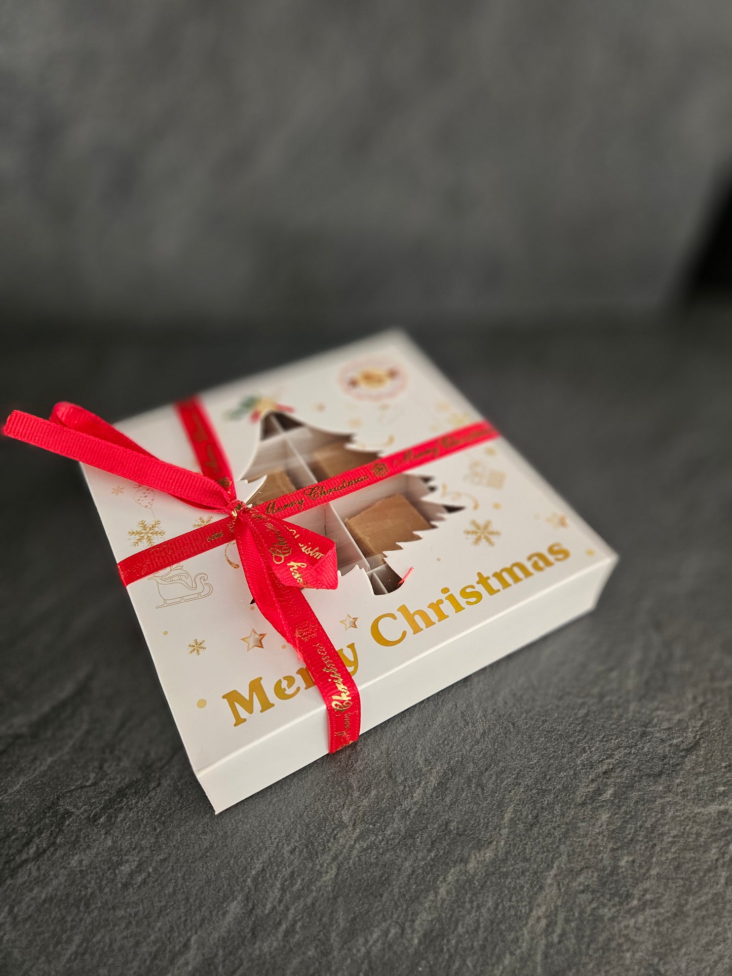 Christmas-themed gift box with a red ribbon on a dark surface