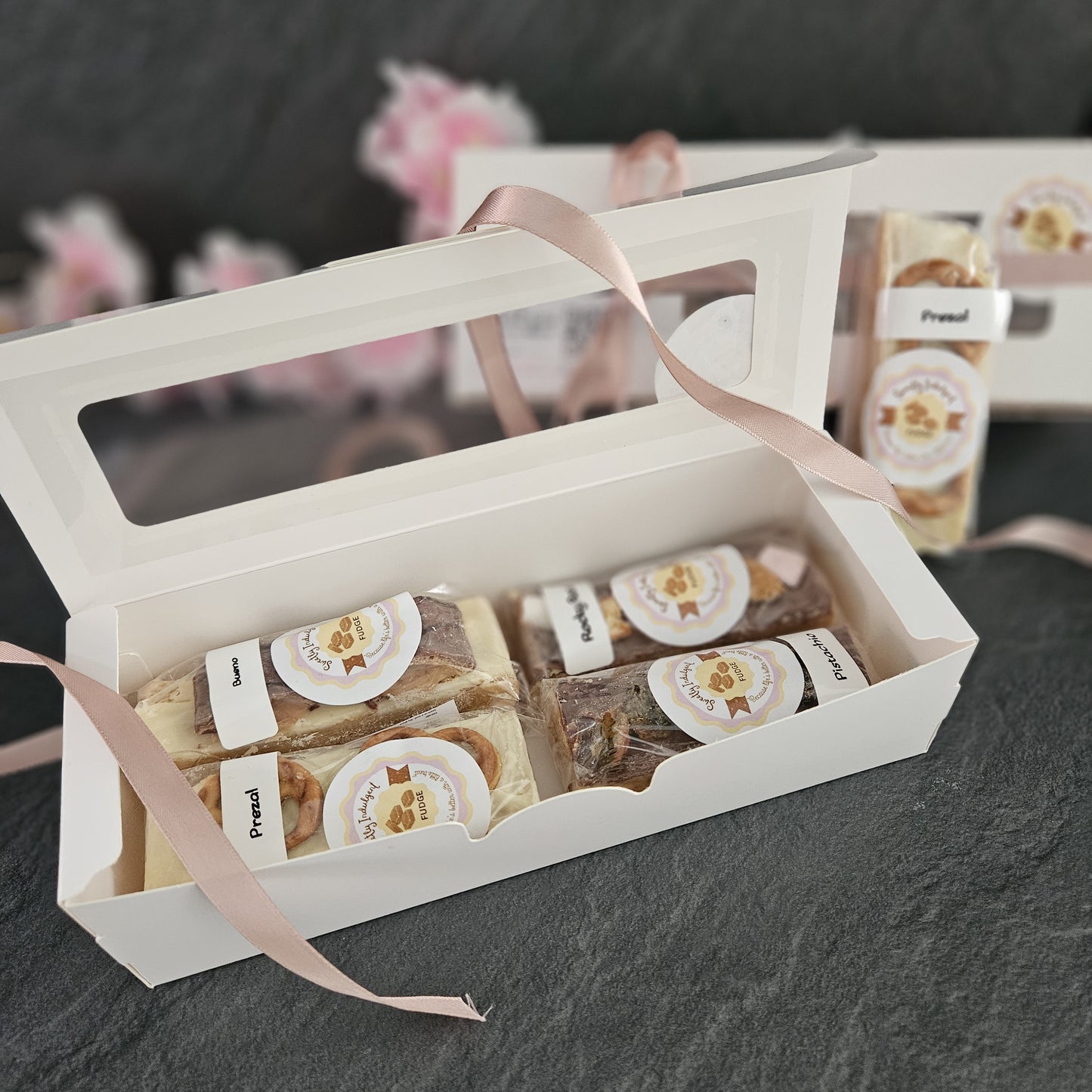 Gift box with four fudge bars and a pink ribbon on a dark surface