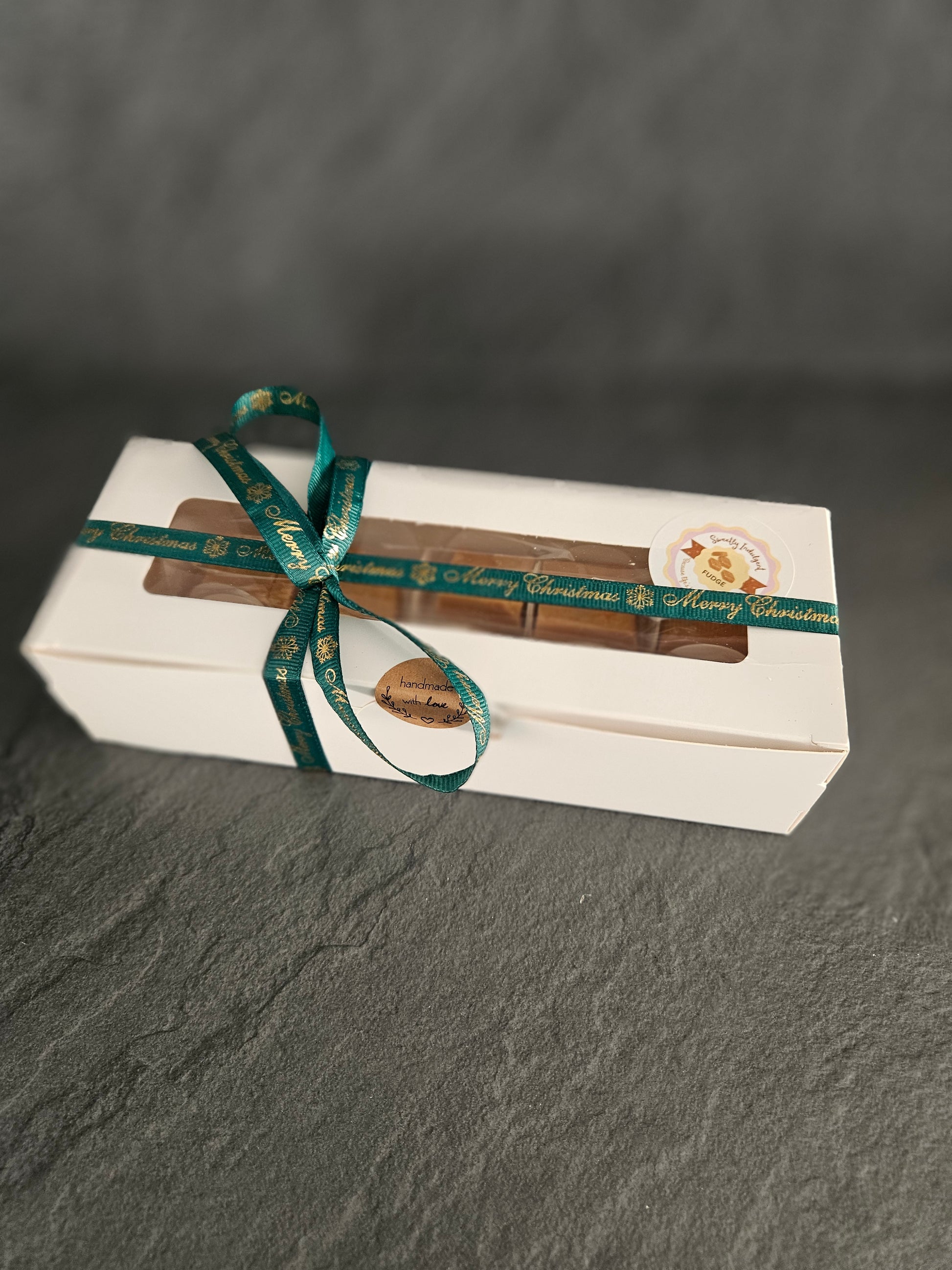 Gift box with 8 fudge pieces and a green ribbon on a dark gray background