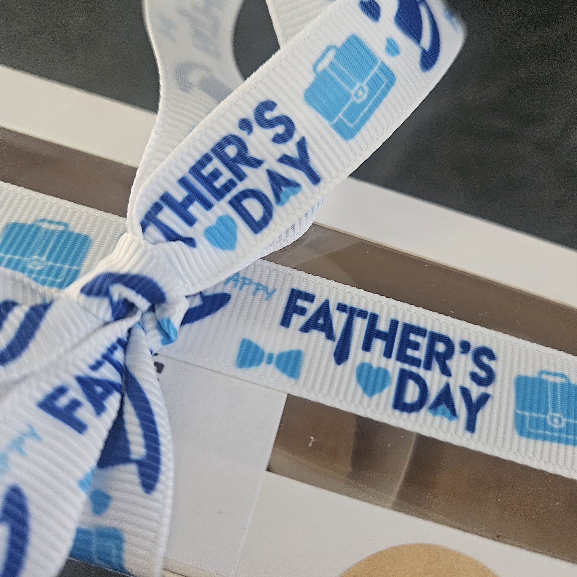 Close up of blue father's day ribbon with white background on box of fudge