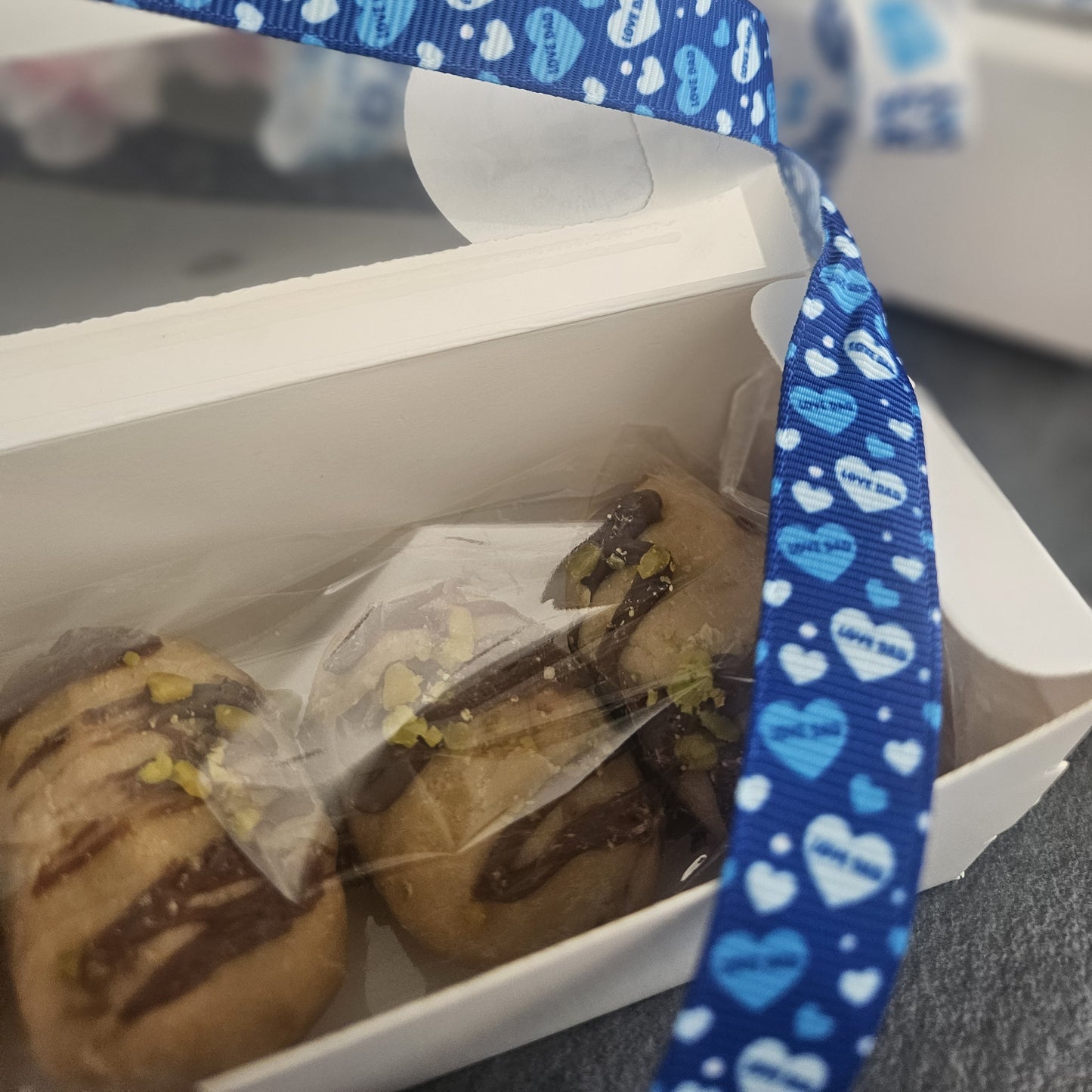 close up of box of fudge open dipped dates with a blue ribbon featuring heart patterns and love dad text.