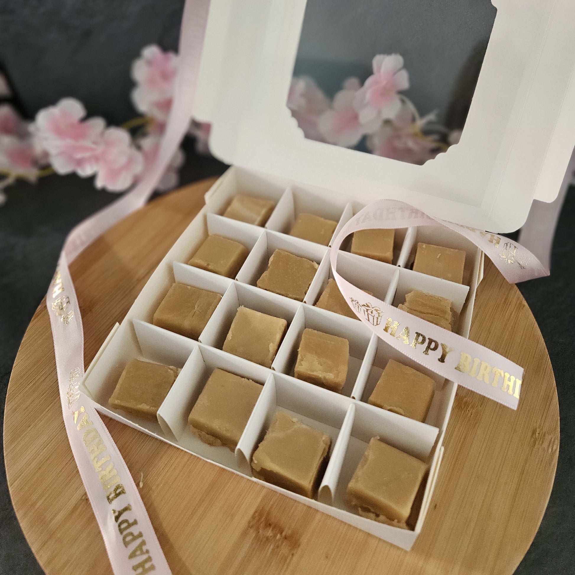 Box of creamy fudge with 'Happy Birthday' ribbon on a wooden surface