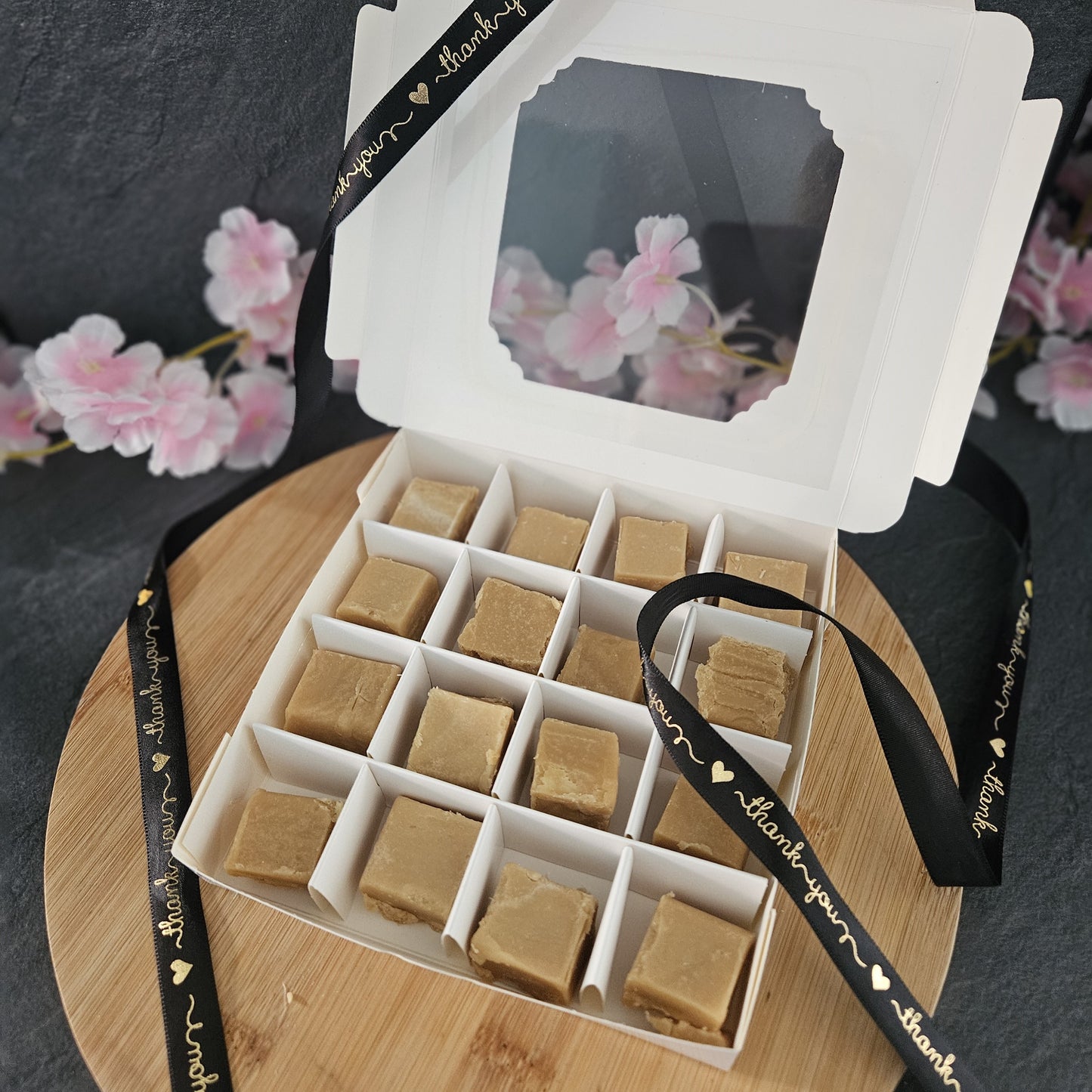 open box of luxury fudge with cherry blossoms in the background. 
