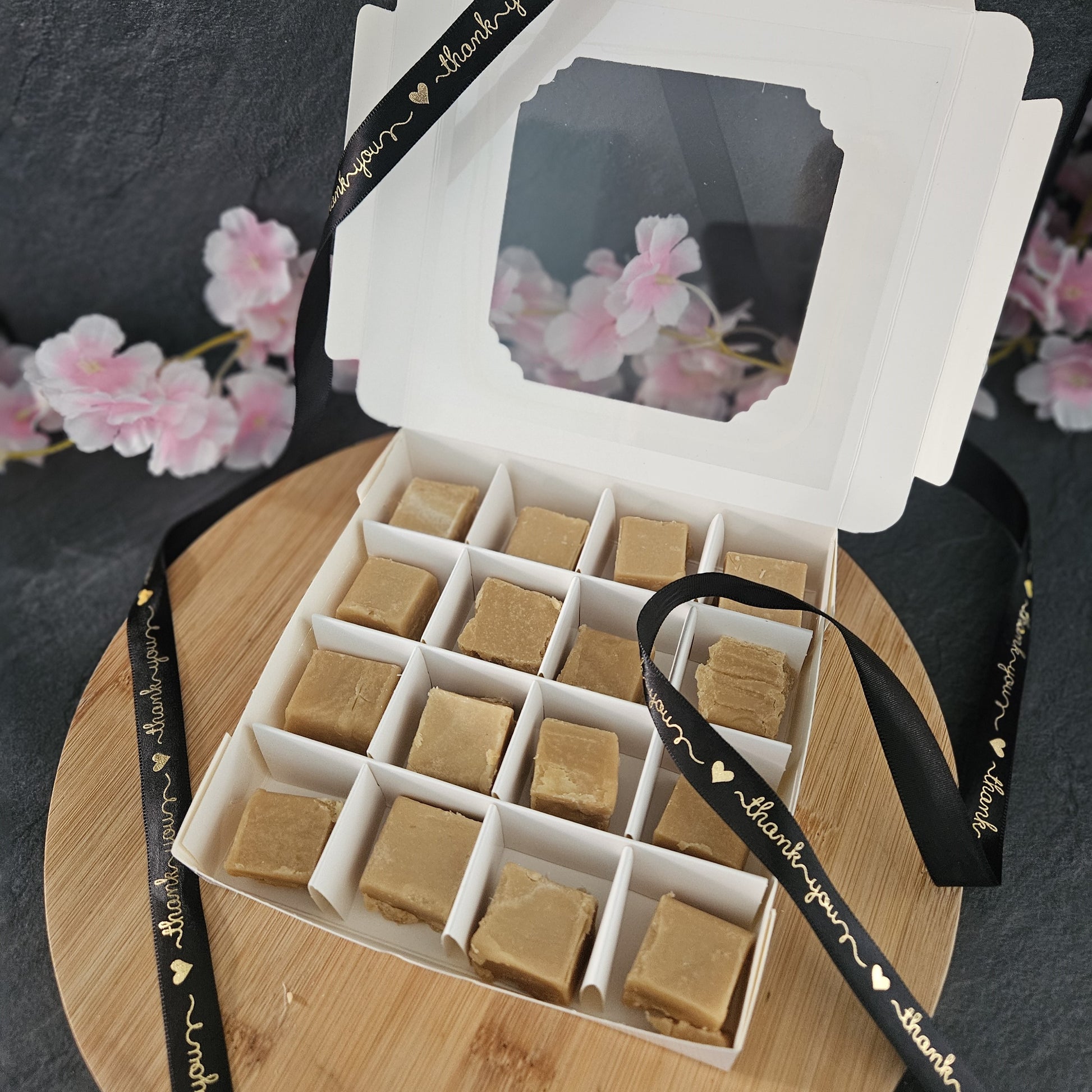 open box of luxury fudge with cherry blossoms in the background. 