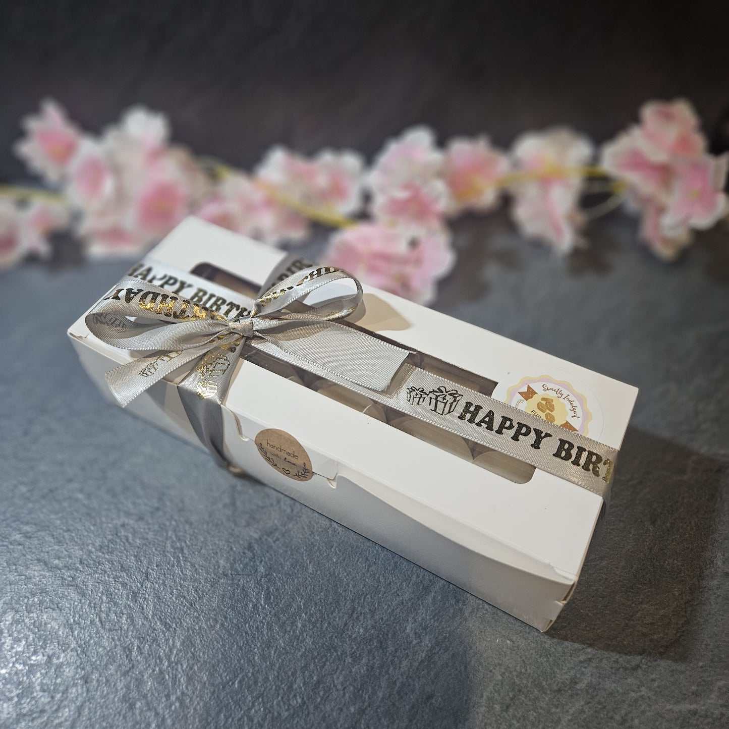white long box with grey Happy Birthday ribbon, with sweetly Indulgent branding.