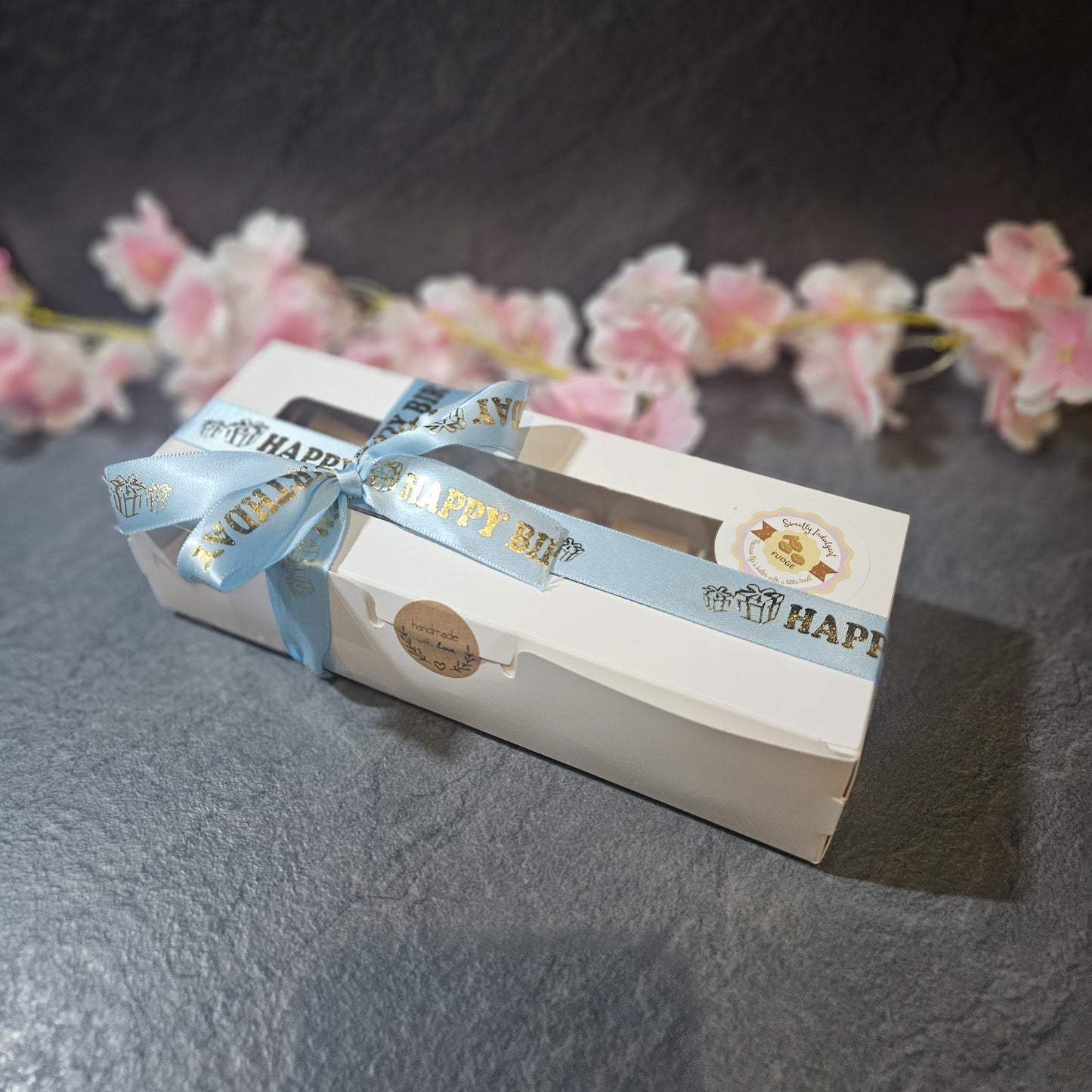 long rectangle box with a baby blue ribbon. Sealed with handmade with love sticker. 