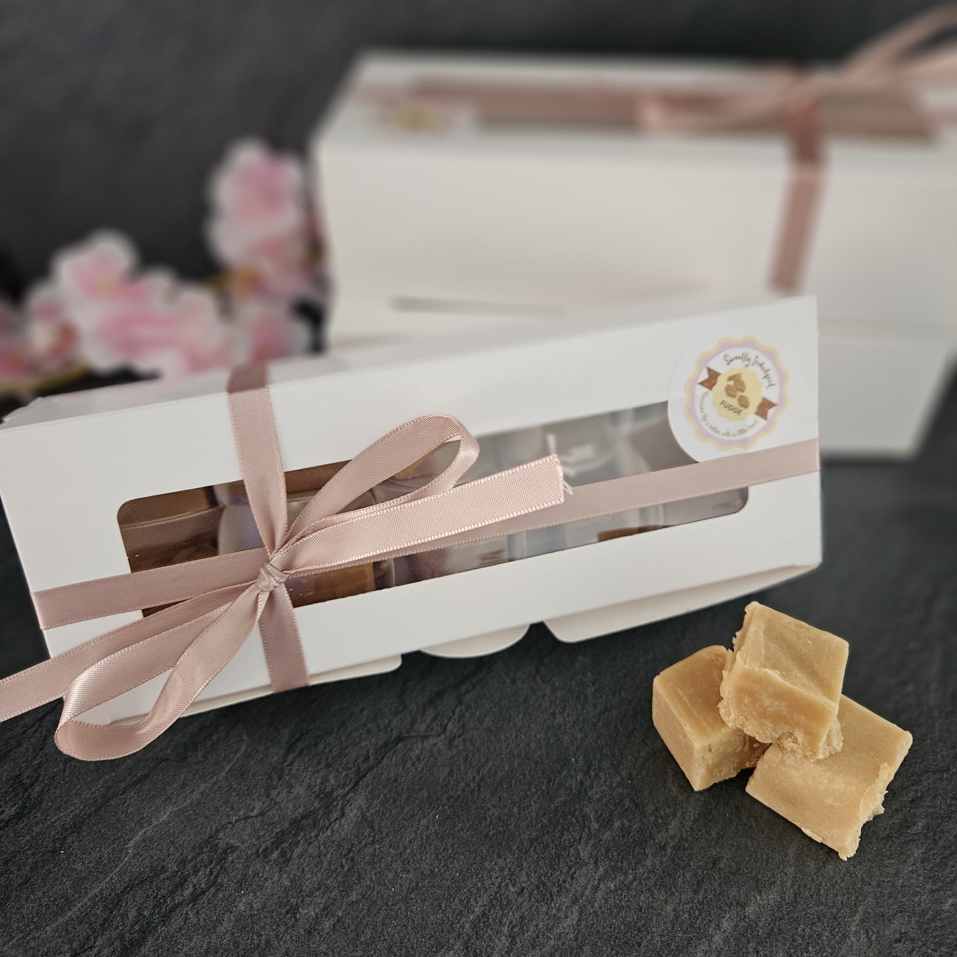 Box of fudge with pink ribbon. fudge pieces in foreground