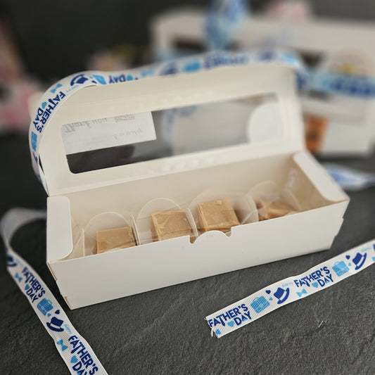 White box with fudge cubes on a dark surface with father's day ribbon