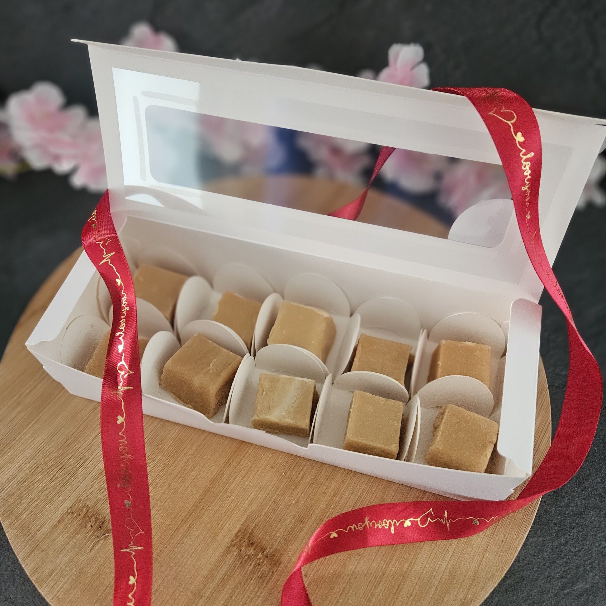 Open rectangular box with 10 pieces of creamy  butter fudge. 