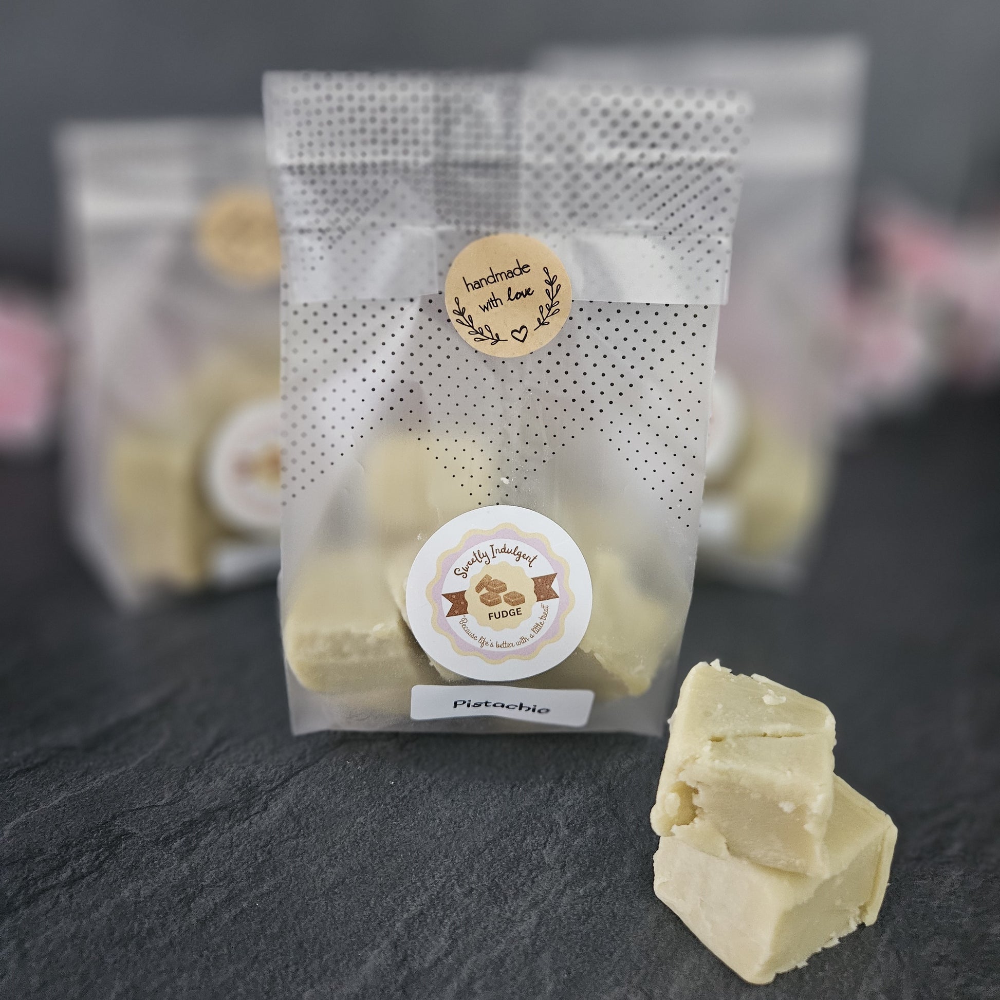 Packaged bag of pistachio fudge with a Sweetly indulgent label on a dark surface