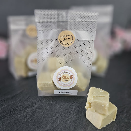 Packaged bag of pistachio fudge with a Sweetly indulgent label on a dark surface
