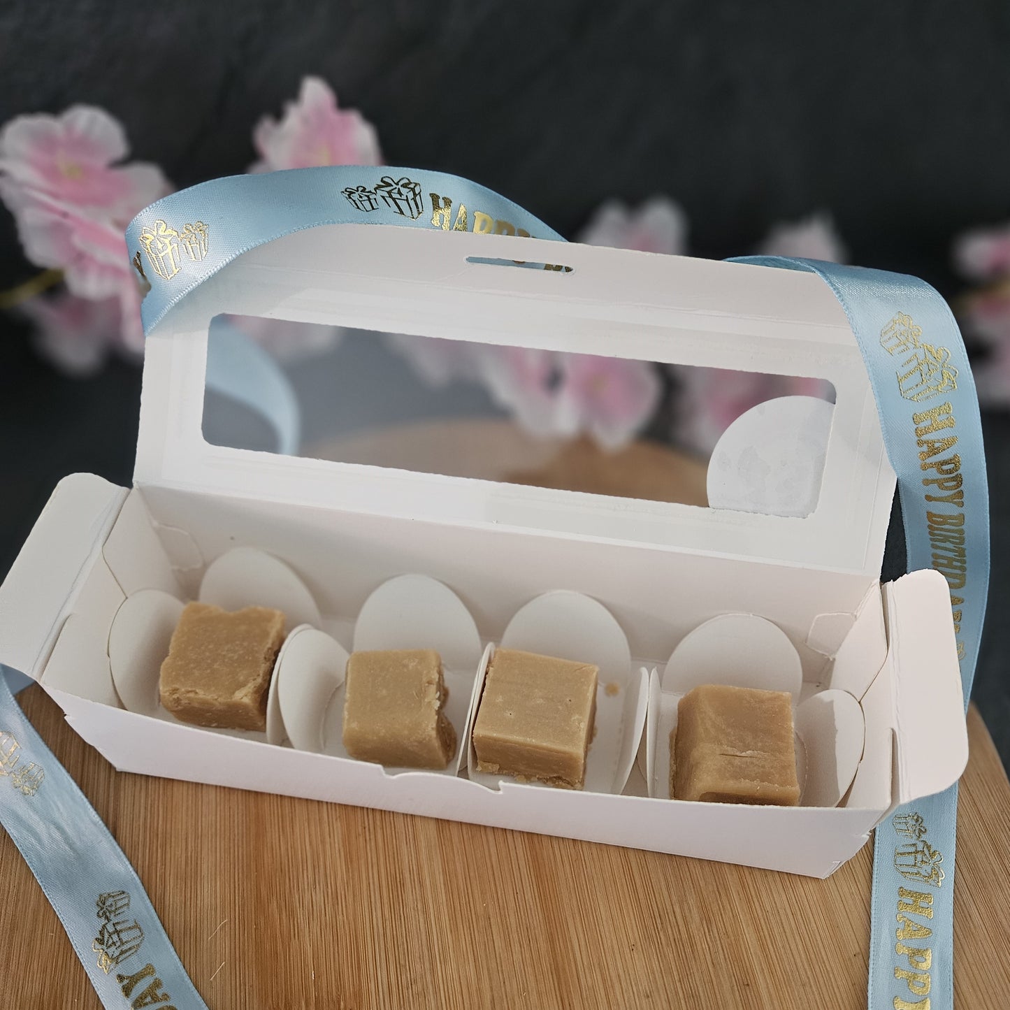 open box of fudge with a 'Happy birthday' blue ribbon on a wooden surface