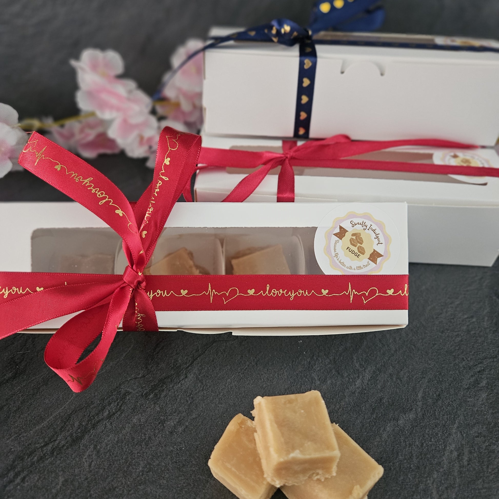 3 Boxes of fudge with the front box with a red ribbon and 'I love you' message on a dark surface.